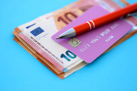 Credit card and pen with euro currency money bills banknotes on light blue background. Business, financial operations and accounting in European Unionの写真素材