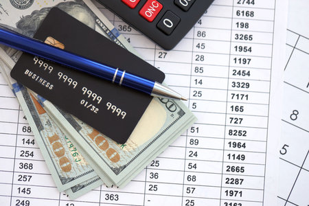Credit card and pen with US dollar currency money bills banknotes on calculations document...