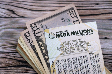 KYIV, UKRAINE - OCTOBER 22, 2025 Mega Millions lottery ticket lies with money on wooden table close upのeditorial素材