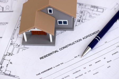 KYIV, UKRAINE - OCTOBER 3, 2025 Residential construction agreement and toy house on white blueprints for construction close upのeditorial素材
