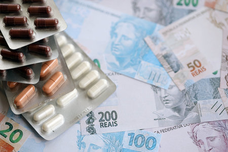 Brazilian reais banknotes and medicine pills. The current Brazil real money bills and drugs lies on table in big amount. The concept of medicine and pharmacy in Brazilの写真素材