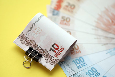 Close up of brazilian reais money bills in big amount on yellow table. Pile of Brazil real currency banknotes. Finance and banking conceptの写真素材