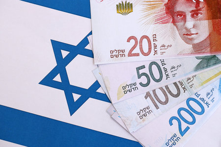 Israel New Shekels banknotes on national flag. The current Israel money bills lies on flag in big amount. The concept of business and investment in Israelの写真素材