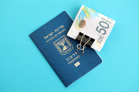 Israel New Shekels banknotes and passport on blue background. The current Israel money bills lies on...