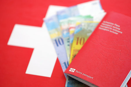 Swiss franc banknotes and passport with tickets on flag. The current francs money bills and biometrical pass lies on flag. The concept of travel and vacation in Switzerlandの写真素材