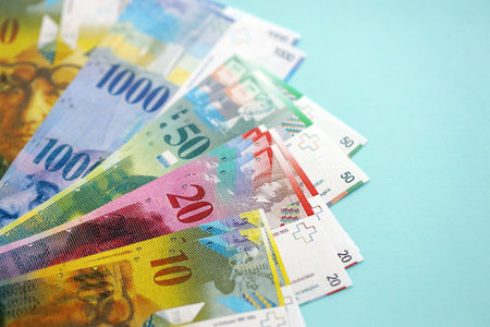 Swiss franc banknotes on blue background. The current francs money bills lies on table in big amount. The concept of business and investment in Switzerlandの写真素材