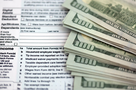 Big amount of United States USD dollar bills banknotes on table with 1040 individual income tax...