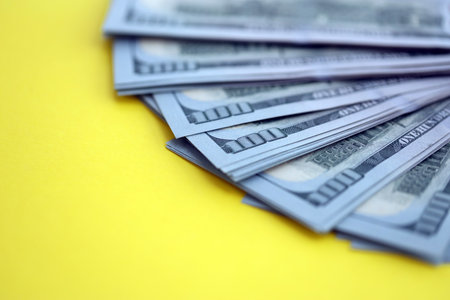 Big amount of United States hundred dollar bills on yellow background. Concept of taxation and money making in United Statesの写真素材