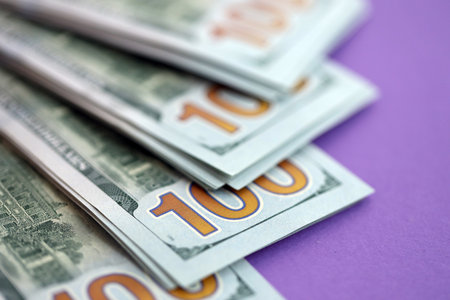 Big amount of United States hundred dollar bills on purple background. Concept of taxation and money making in United Statesの写真素材