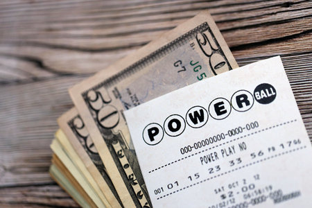 KYIV, UKRAINE - OCTOBER 22, 2025 Power Ball lottery ticket lies with money on wooden table close upのeditorial素材