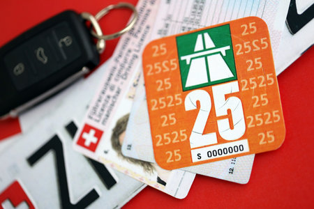 Switzerland vignette sticker for 2025 year and license plate with ignition key on Swiss flag close up. Driving permit and registration conceptの写真素材