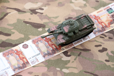 Russian rubles money bills and tank on camouflage fabric close up. Concept of russian army funds and...