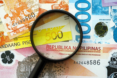 Philippines peso currency money bills and magnifying glass close up. The concept of financial monitoring and taxationの写真素材