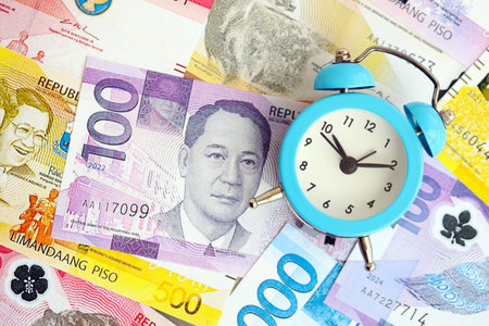 Philippines peso currency money bills and alarm clock close up. The concept of time management and...