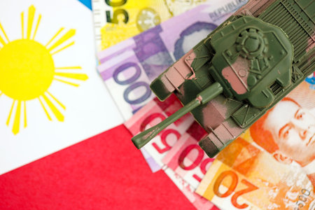 Philippines peso currency money bills and toy tank on flag close up.の写真素材