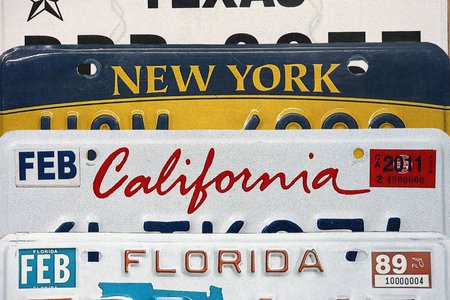 Old US car license plates with various state names close up. Concept of driving in United States. Reaching a car registration