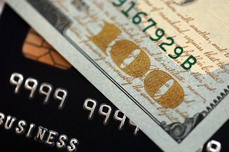 One hundred US dollar bill banknote on black credit card for banking and payments. Concept of business and bank serviceの写真素材