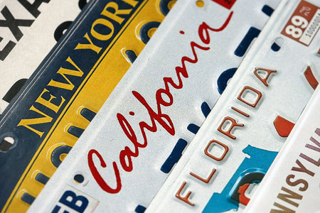 Old US car license plates with various state names close up. Concept of driving in United States. Reaching a car registrationの写真素材
