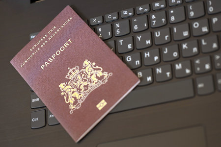 Netherlands passport lies on black laptop keyboard buttons background close up. Technologies and control in Europe conceptの写真素材