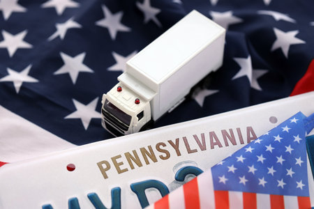 Toy truck and USA state of Pennsylvania license plate on US flag. Concept of driving in Pennsylvania. Reaching a driving permitの写真素材