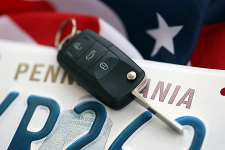 Remote control car keys on Pennsylvania license plate on US flag. Concept of driving in Pennsylvania. Reaching a driving permitの写真素材