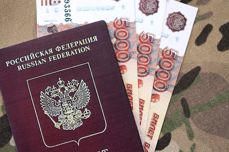 Russian passport with money on multicam camouflage fabric close up. Concept of russian army fundsの写真素材
