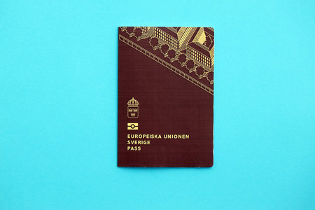 Swedish biometrical passport on light blue table background. Concept of citizenship of Swedenの写真素材