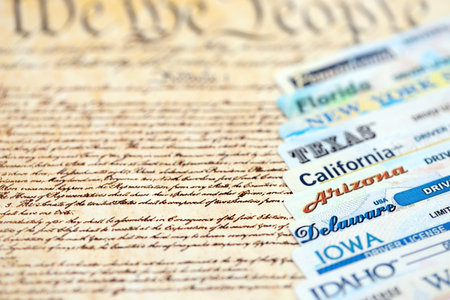Big amount of driving licenses from different USA states on constitution page. Stack of driving license specimen cardsの写真素材