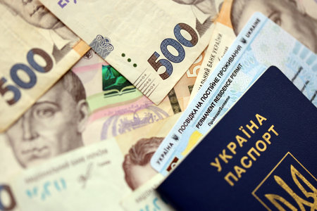 Ukrainian residence permit card or permanent resident card with passport on Ukrainian money close upの写真素材