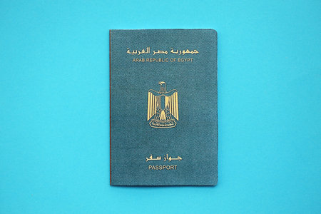 Egyptian passport book on light blue paper background close up. Travel document on blue surface