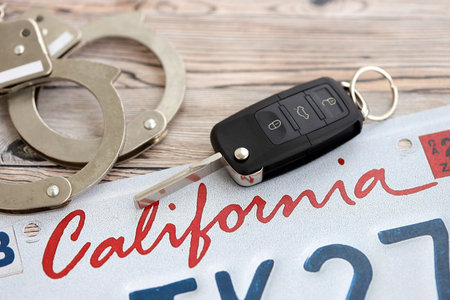 Remote control car keys on California license plate and handcuffs. Concept of car accident in California.の写真素材