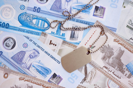 United Arab Emirates dirham currency money bills and military token close up. The concept of army...