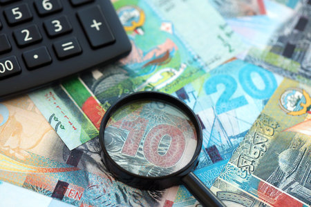 Kuwaiti dinar currency money bills and calculator with magnifying glass close up. The concept of...