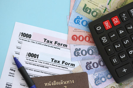 Thai baht money bills and calculator with tax form close up on blue. Taxation and accounting concept