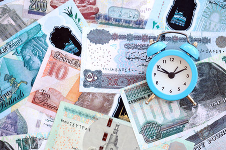Egyptian pound currency money bills and alarm clock close up. The concept of time management and...