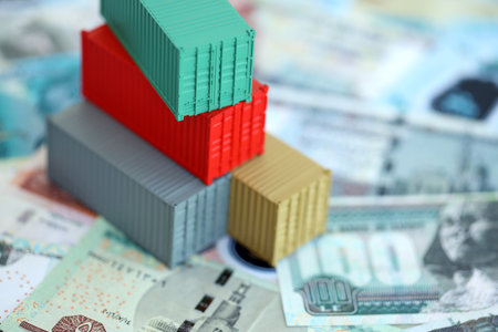 Egyptian pound currency money bills and toy cargo containers close up. The concept of shipping and...