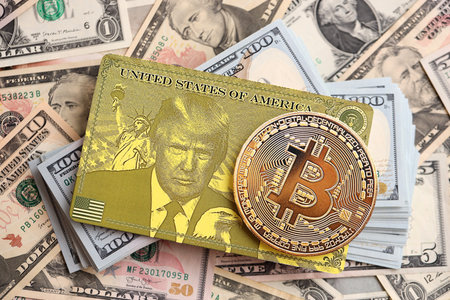 KYIV, UKRAINE - DECEMBER 13, 2025 Trump gold card and bitcoin on big amount of US dollar money bills...