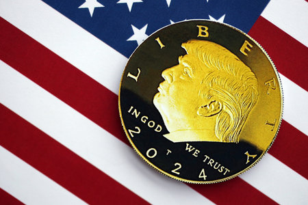 KYIV, UKRAINE - DECEMBER 13, 2025 Trump gold coin on United States of America flag with stars and...