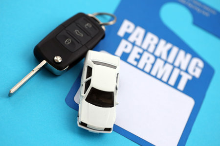 Parking permit paper notice tag for car interior with ignition keys and toy car. Parking permit for...