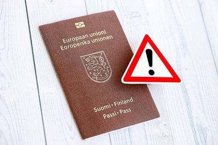 Finland passport with exclamation sign on white wooden background close up. Problems with citizenship in Europe conceptの写真素材