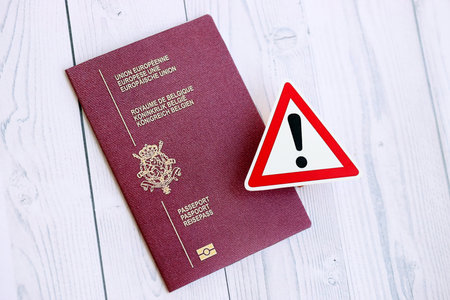 Belgium passport with exclamation sign on white wooden background close up. Problems with citizenship in Europe conceptの写真素材