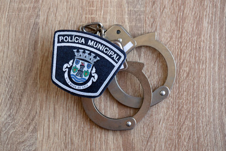 KYIV, UKRAINE - SEPTEMBER 6, 2025 Portugal Municipal Police patch and old metal handcuffs on table close upのeditorial素材