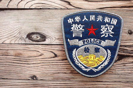 KYIV, UKRAINE - SEPTEMBER 17, 2025 Chinese Police badge on brown wooden table surface close upのeditorial素材