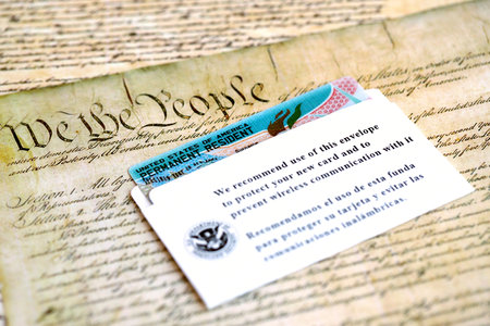 KYIV, UKRAINE - AUGUST 31, 2025 Permanent resident green card in envelope lies on US constitution...
