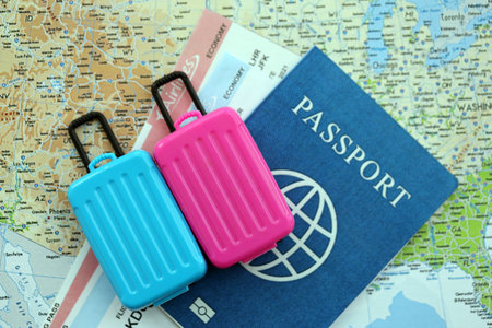 Passport with boarding pass tickets and toy luggage bag on United States map close up