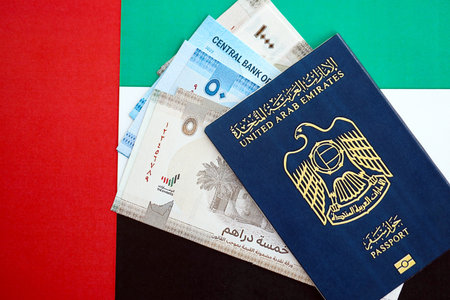 United Arab Emirates dirham currency money bills and passport lies on flag close up. The concept of...