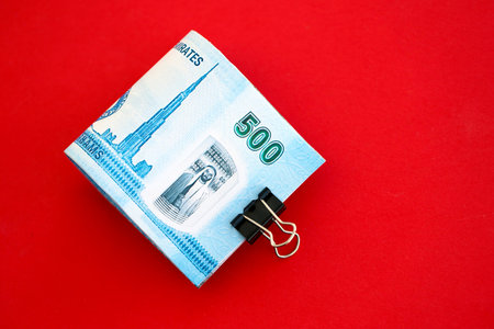 United Arab Emirates dirham money bills in big amount on red close up. Finance and banking concept