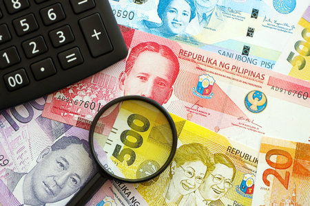 Philippines peso currency money bills and calculator with magnifying glass close up. The concept of...