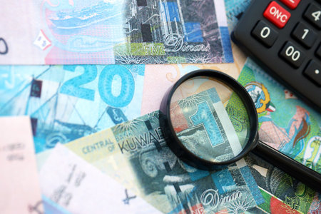 Kuwaiti dinar currency money bills and calculator with magnifying glass close up. The concept of...