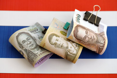 Thai baht currency money bills lies on flag close up. The concept of business and investment